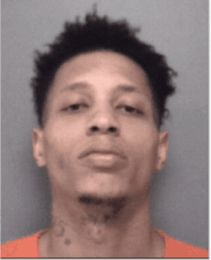 Head shot of young black man, with short black hair and some chin hair.