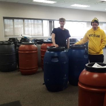 An image of two volunteers during a previous rain barrel and composter sale pick-up event.