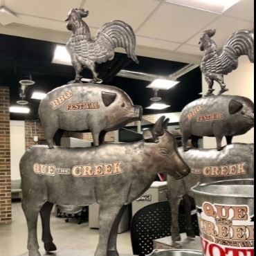Large silver trophies with base, then cow, pig, and chicken on top of each other. 