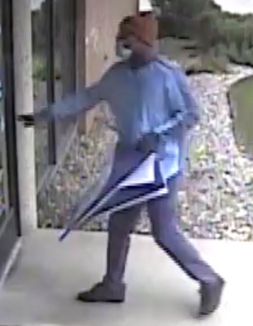 Thin black man in dark pants, light blue long sleeve shirt, brown Carhartt hat, with glasses.